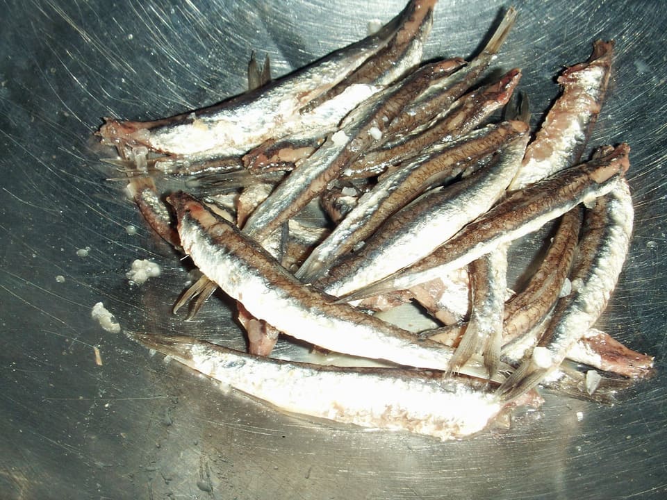 Солёные анчоусы целиком с крупинками соли в металлической миске