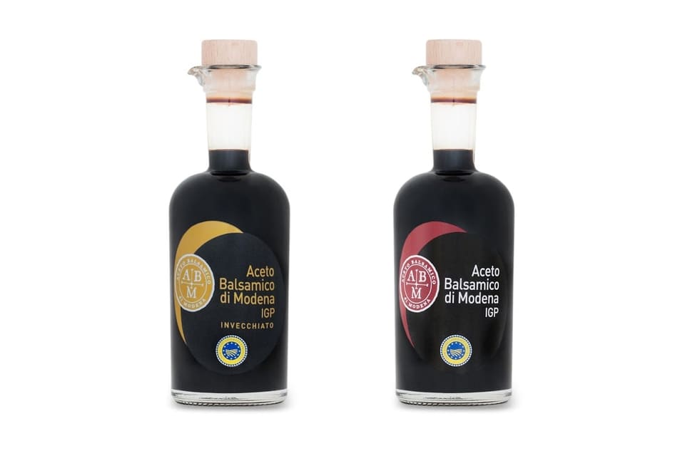 Две тёмные бутылки бальзамического уксуса Aceto Balsamico di Modena IGP на белом фоне