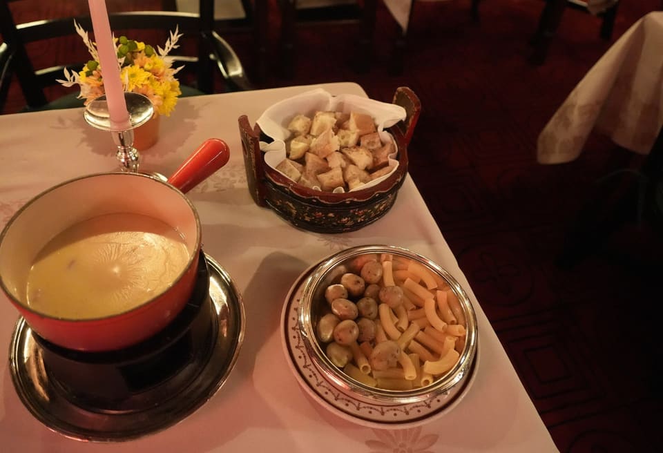 Кастрюлька с расплавленным сыром для фондю и миски с кубиками хлеба