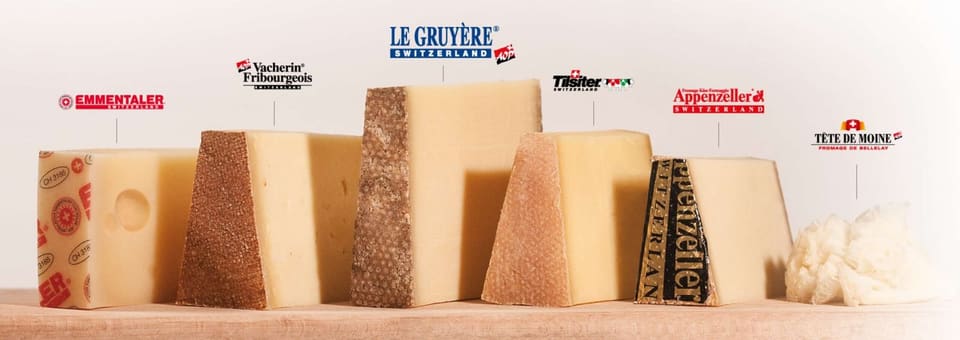 Куски швейцарских сыров с табличками Le Gruyère, Emmentaler и Tête de Moine