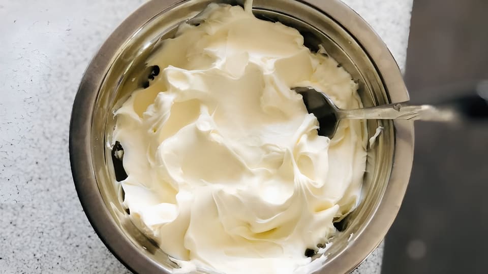 Густой маскарпоне в металлической миске с ложкой